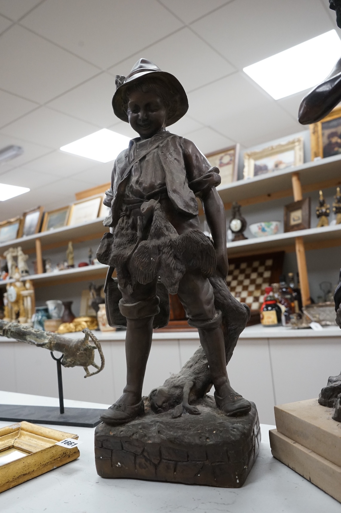 A bronze figure of a young boy carrying dead game, signed August, and a classic bronze of a young boy holding a fish, indistinctly signed, largest 53cm high